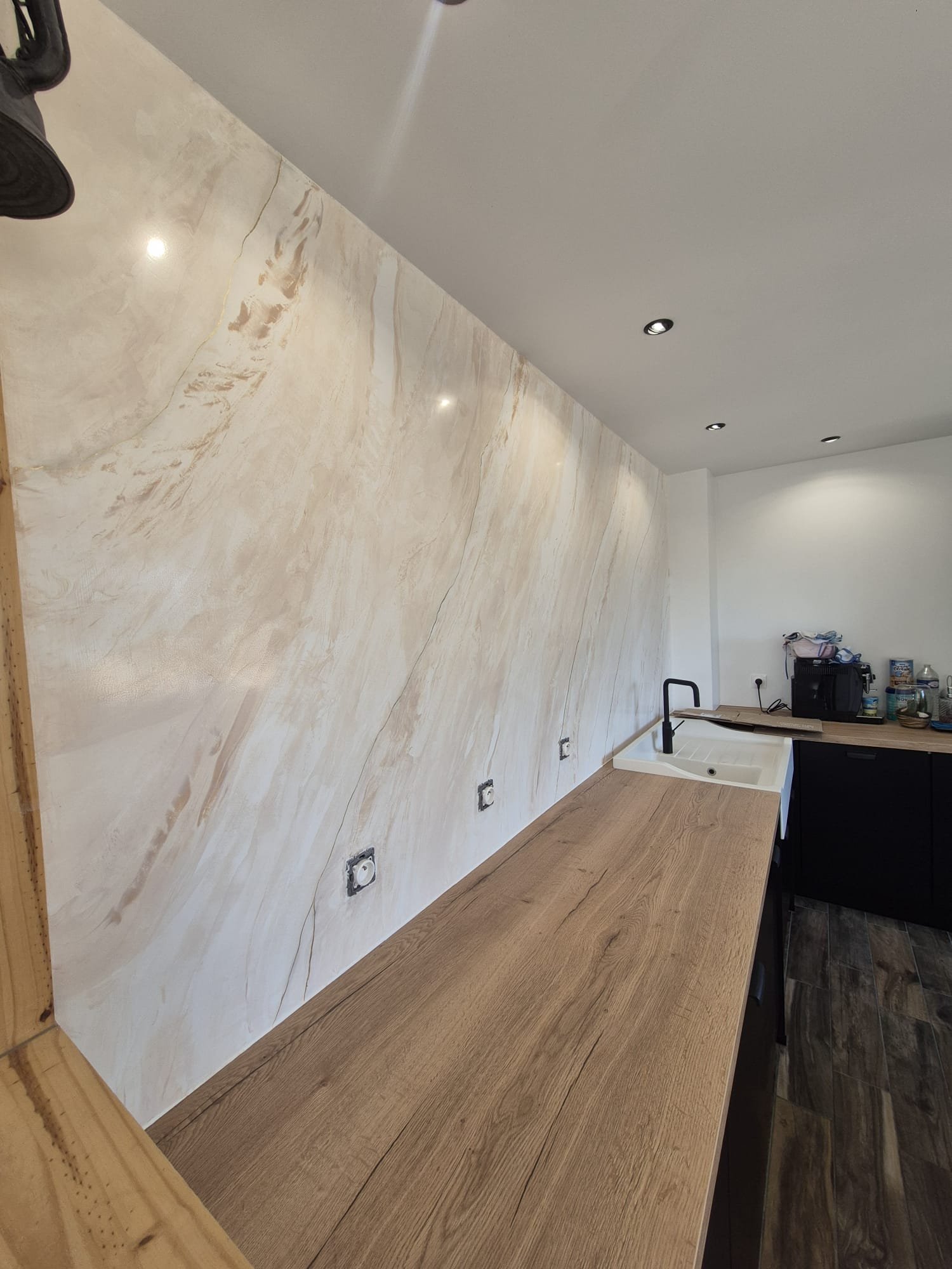 Mur en stucco beige, effet marbre, dans une cuisine moderne, plan de travail en bois
