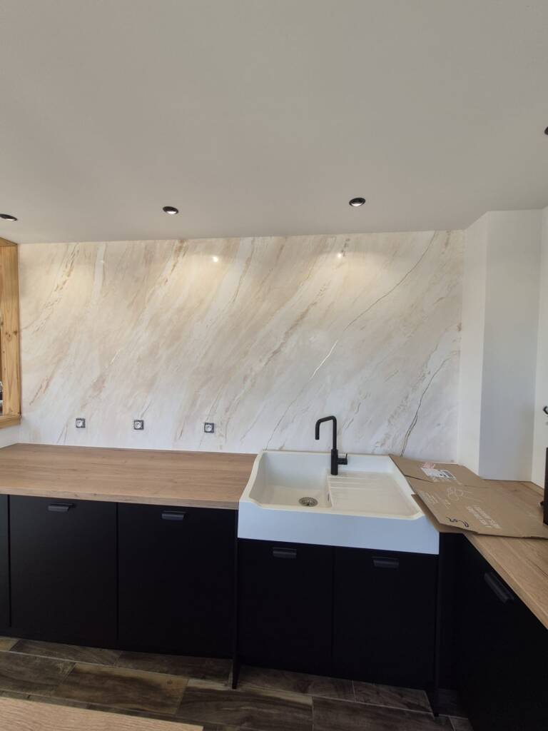 Mur en stucco beige, effet marbre, dans une cuisine moderne, plan de travail en bois, meubles noirs