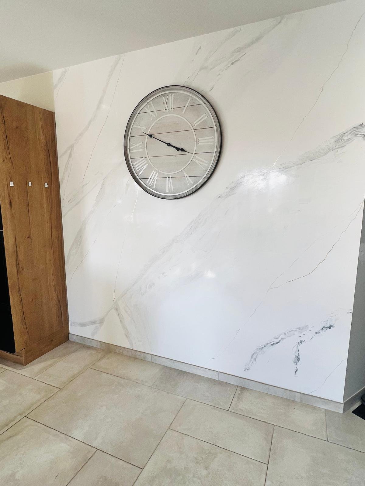 Mur en stucco effet marbre blanc dans une cuisine. Horloge décorative posée au mur.